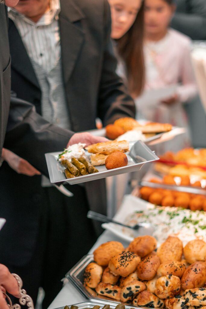 A business event with adults enjoying a diverse buffet featuring bread, pastries, and salads.